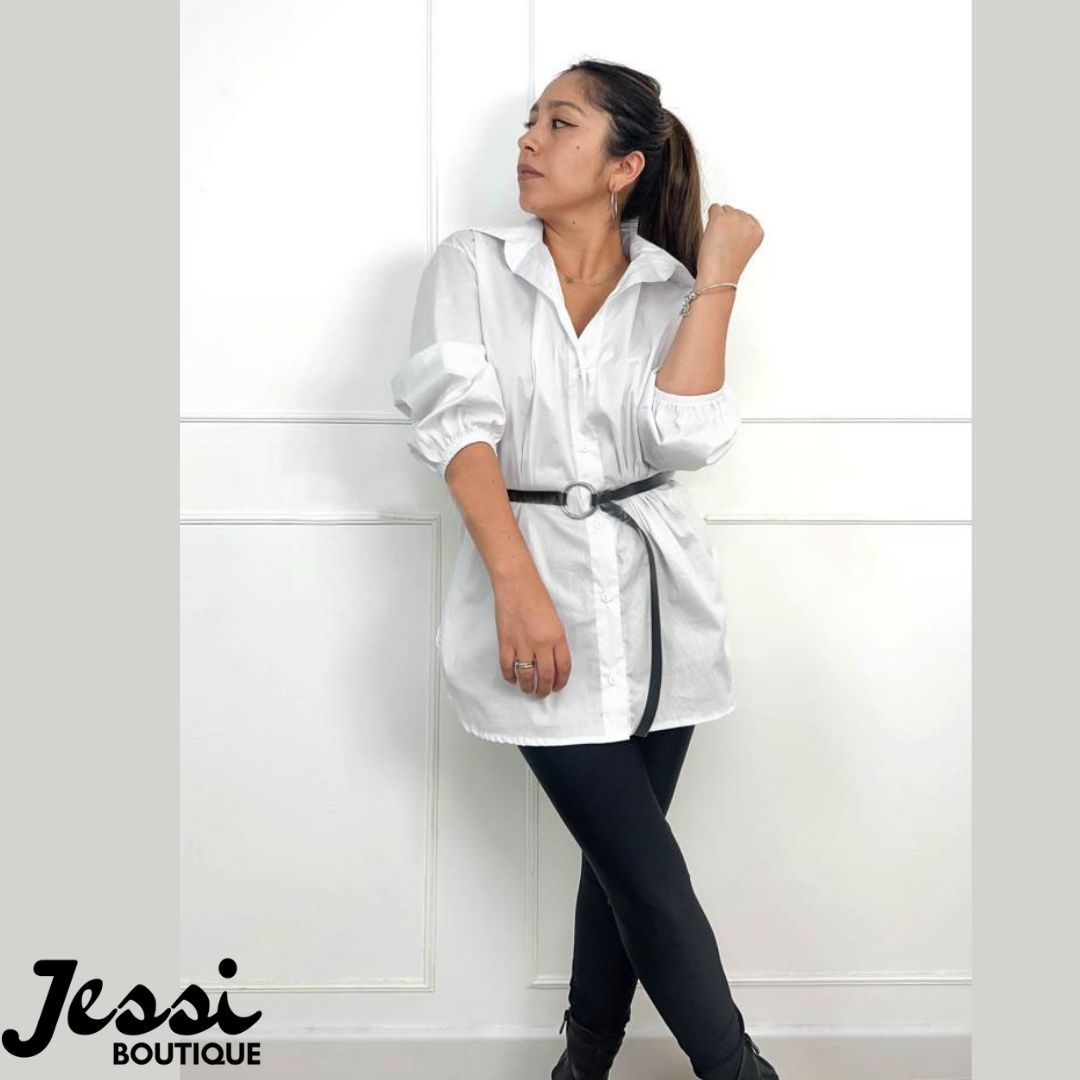 Blusa camisera larga oversize blanca de popelina, manga 3/4 abullonada con resorte y cuello clásico. Modelo usando lazo negro y leggings. Jessi Boutique.