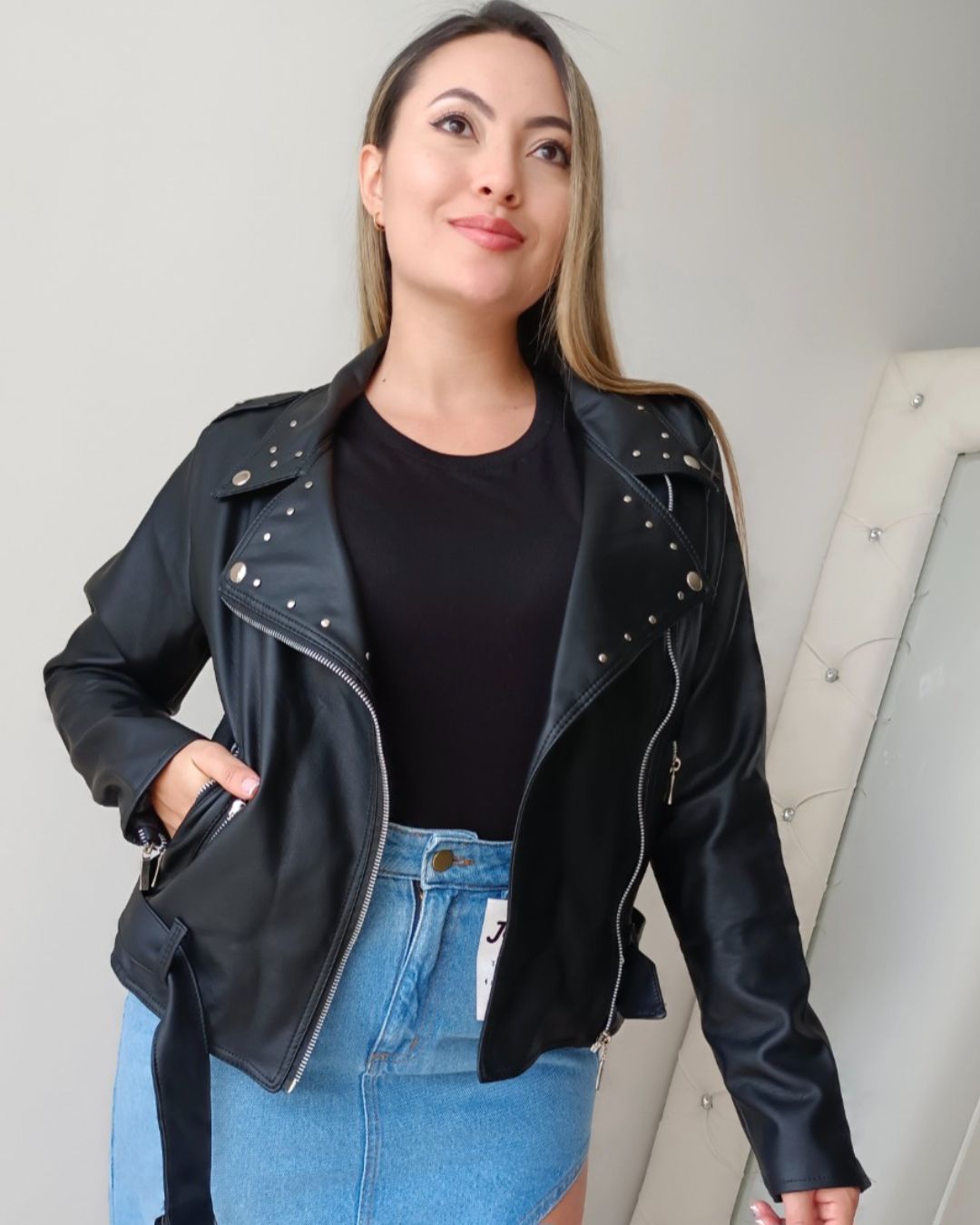 Chaqueta biker de mujer en cuerina negra con cremallera asimétrica, solapas y tachas metálicas. Forro interno. Jessi Boutique.