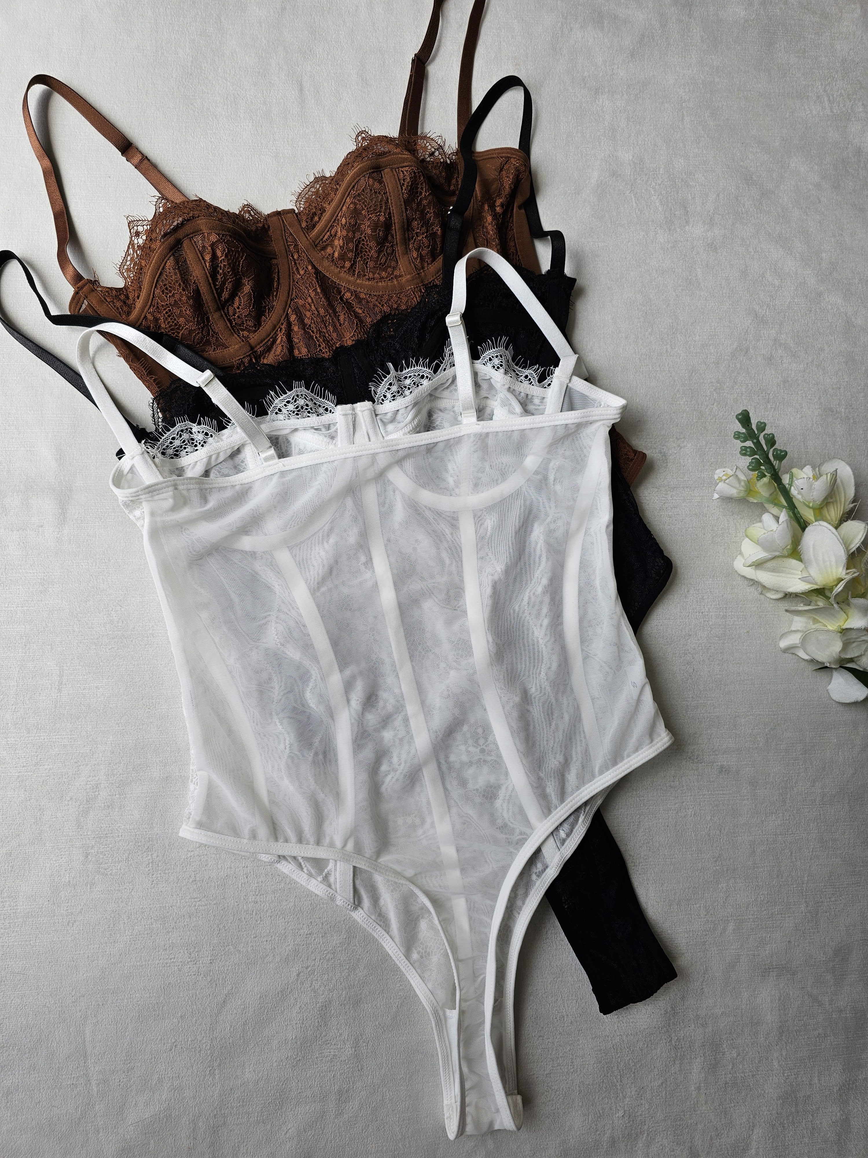 Body tipo corset para mujer en encaje floral con varilla y copas. Body de lencería elegante con tirantes ajustables disponible en blanco, negro y terracota. Prenda sofisticada en tallas S, M, L y XL en Ibagué. Jessi Boutique.