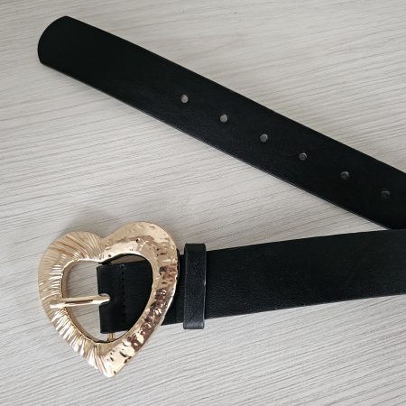 Cinturón negro para mujer con hebilla dorada grande en forma de corazón. Correa de cuero sintético con herraje metálico texturizado. Accesorio de moda para marcar la cintura. Jessi Boutique Colombia.