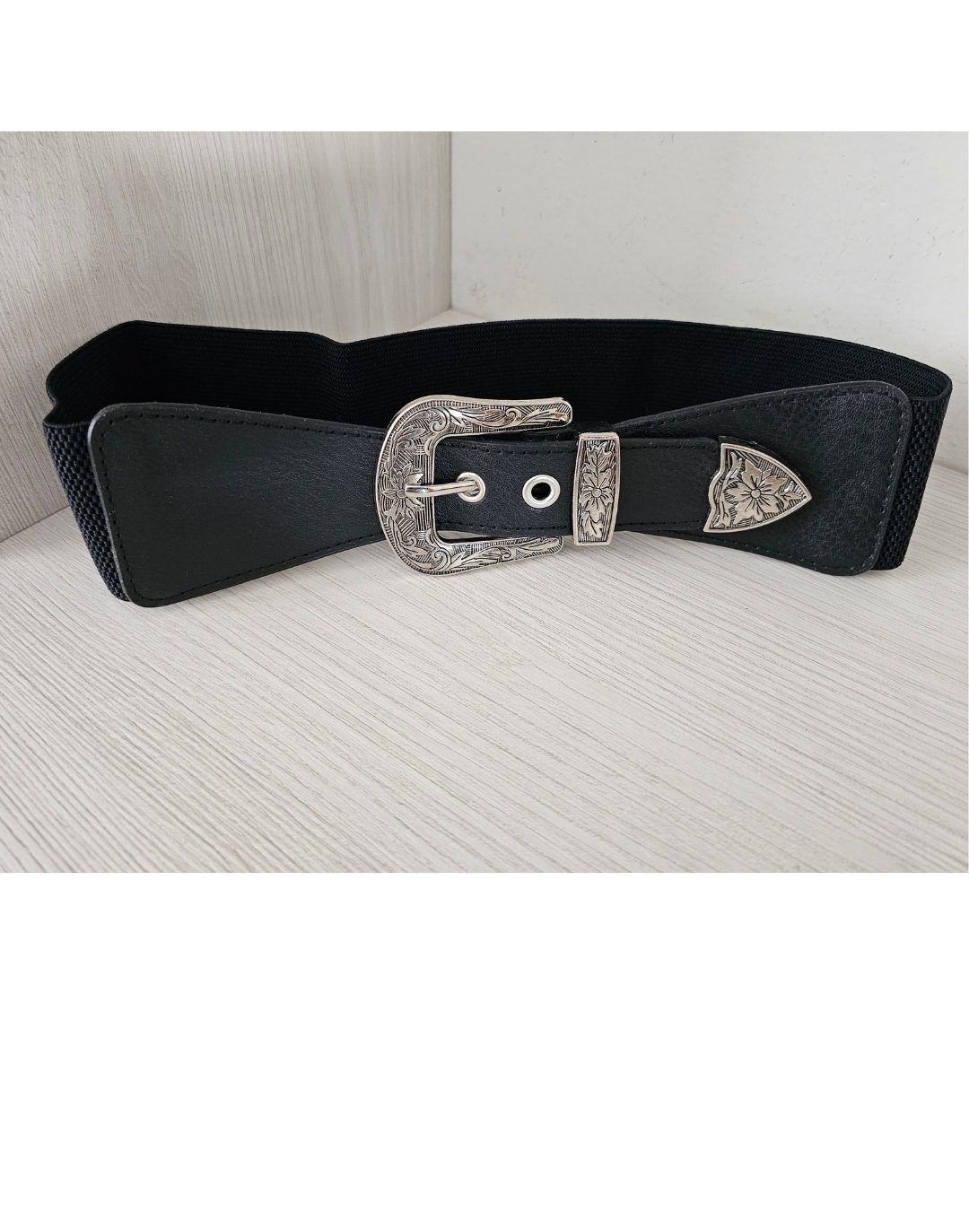 Cinturón fajón elástico para mujer en color negro con hebilla metálica plateada labrada. Accesorio ancho con pasador y punta decorativa de estilo vintage western. Talla única ajustable. Jessi Boutique.