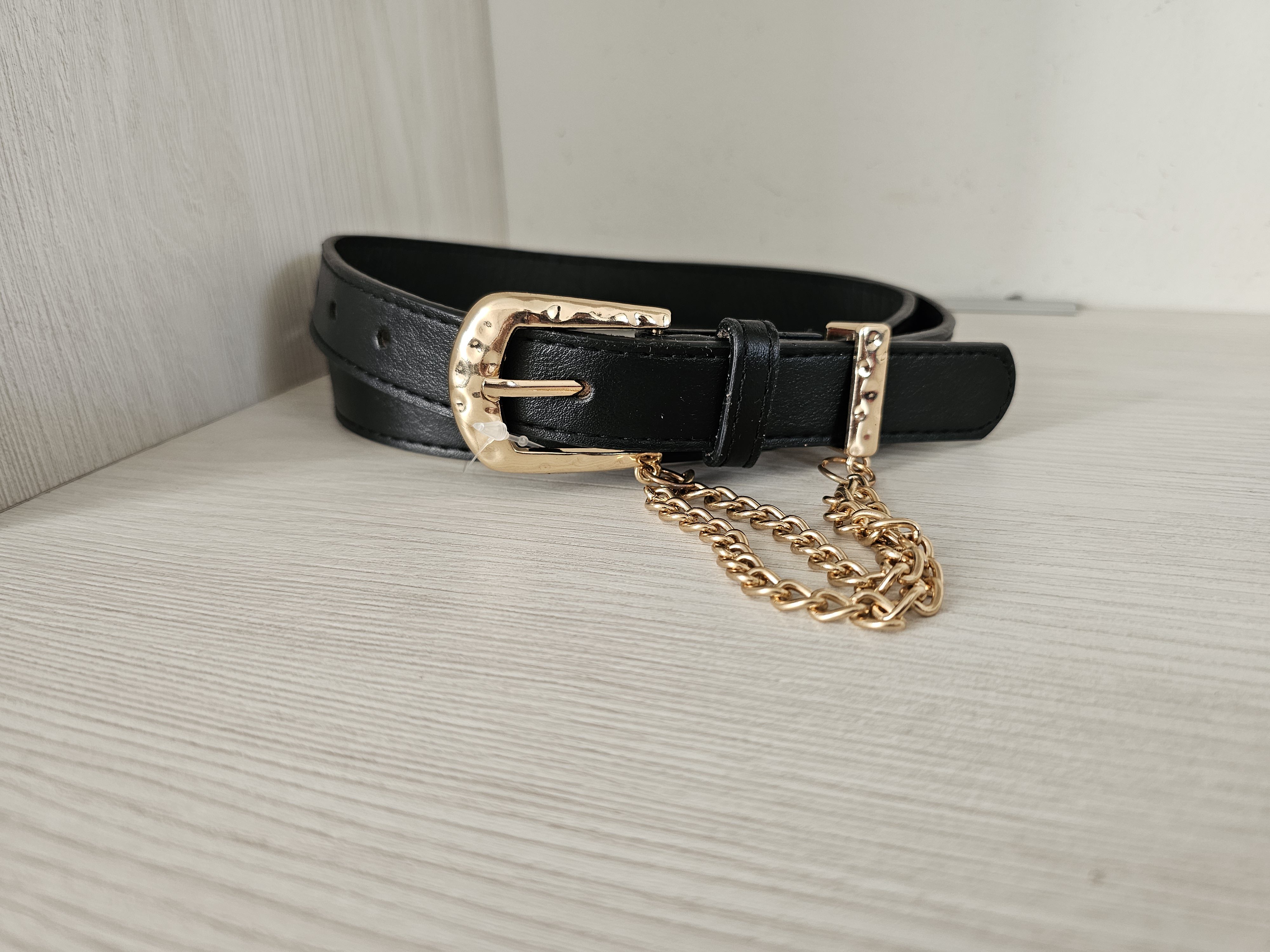 Cinturón sastre negro para mujer con doble cadena dorada y hebilla metálica texturizada. Cinturón delgado de cuero sintético con herrajes dorados. Accesorio elegante para pantalones de tiro alto. Jessi Boutique.
